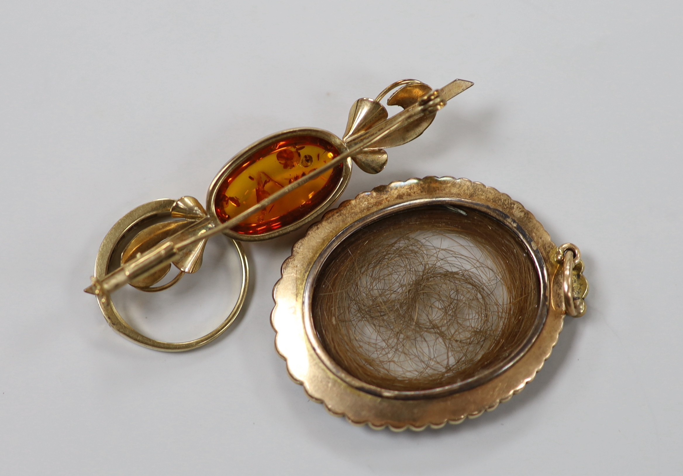 A 19th century yellow metal and split pearl mounted glazed mourning locket pendant containing a lock of hair, overall 48mm, a modern 9ct gold and gem set half hoop ring and a 9ct gold and amber set brooch.